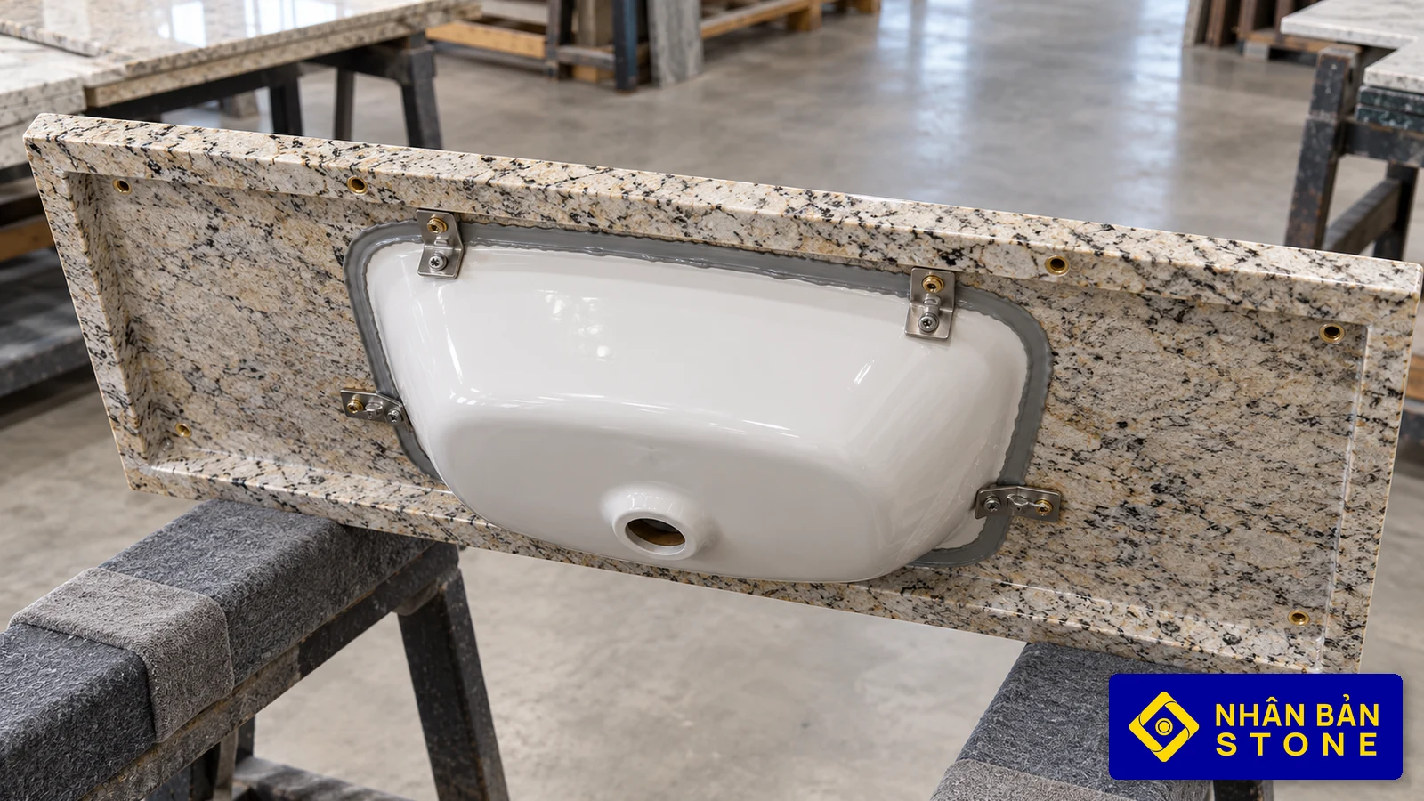 Illustrative image: Underside of stone vanity top with undermount basin secured by stainless steel clips and structural adhesive – NHAN BAN STONE